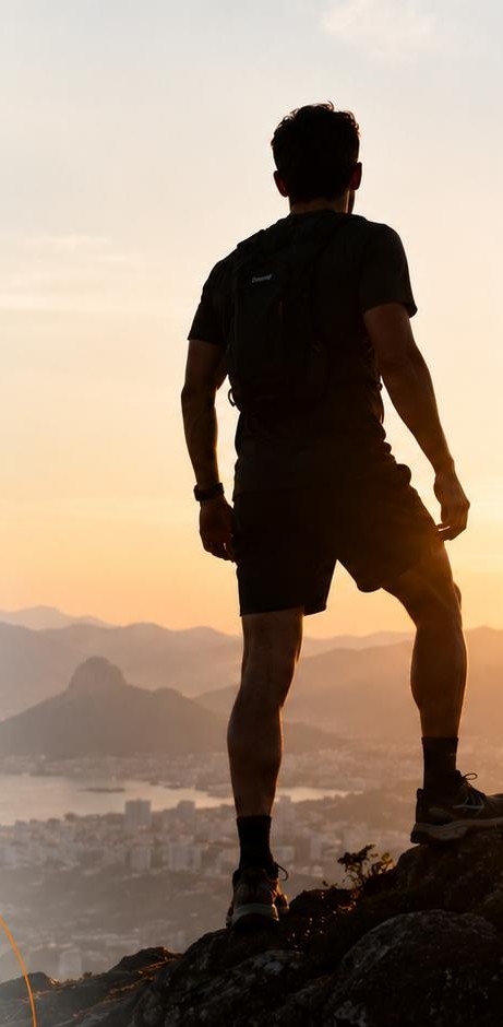 Atleta no alto da montanha olhando o nascer do sol